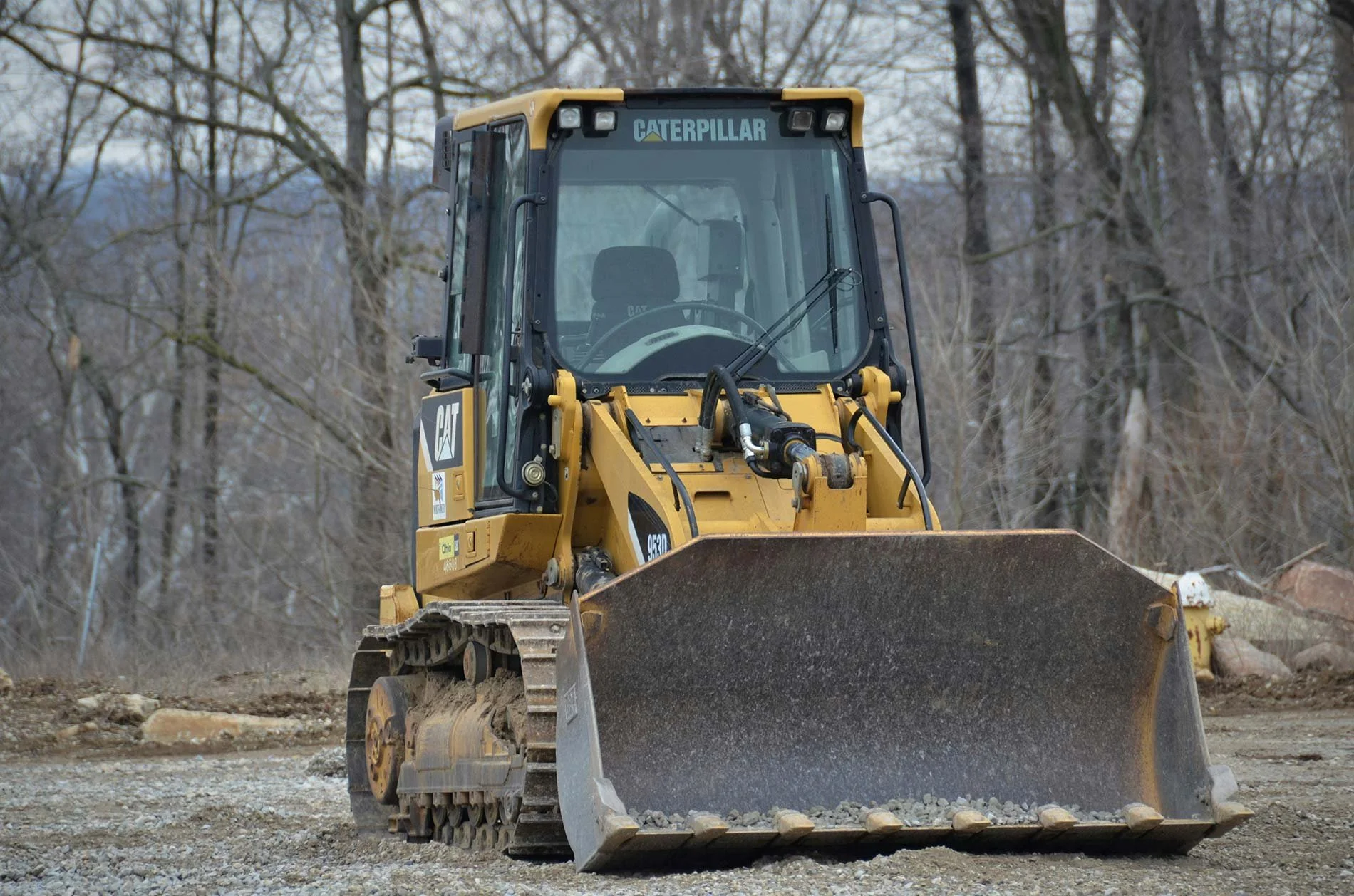 Front view of a Caterpillar tracked loader sitting on cleared dirt at a worksite