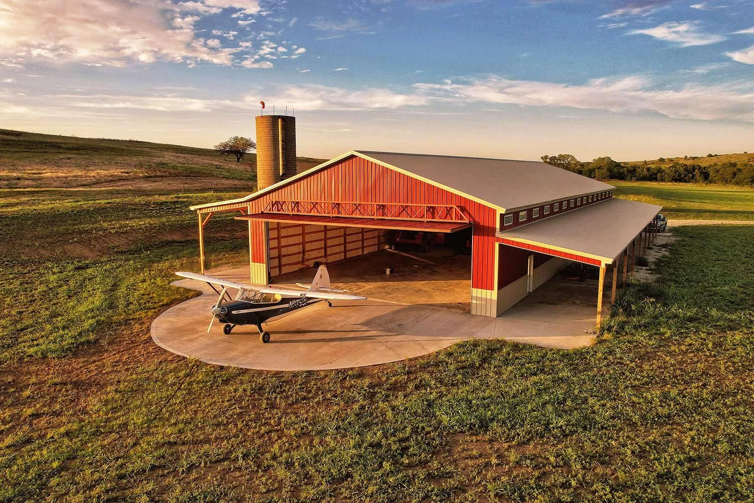 Large red metal building with airplane on a rural property