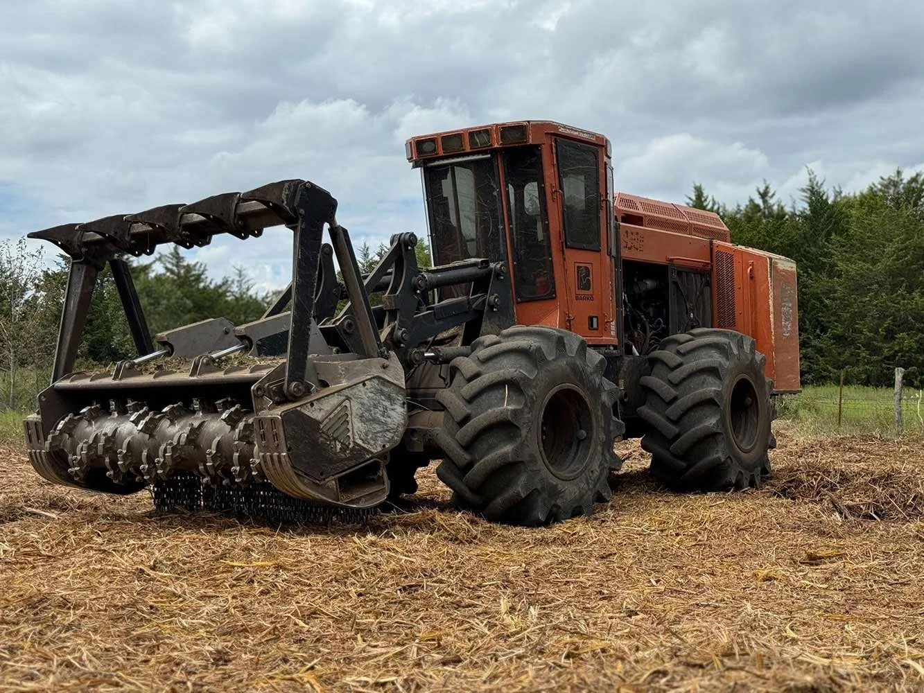 Heavy red forestry mulching machinery parked atop freshly mulched vegetation