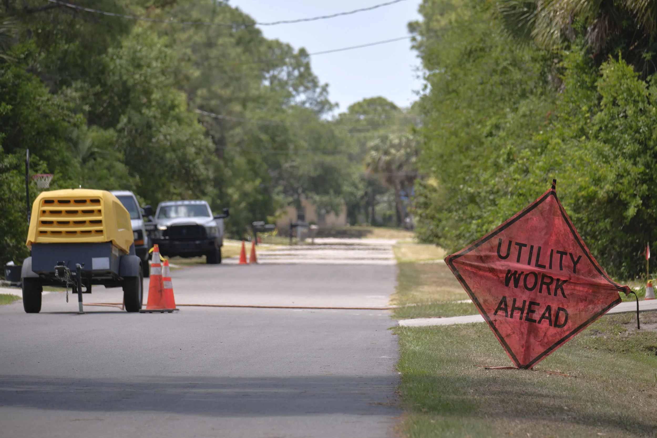 A “UTILITY WORK AHEAD” sign next to a road with traffic cones