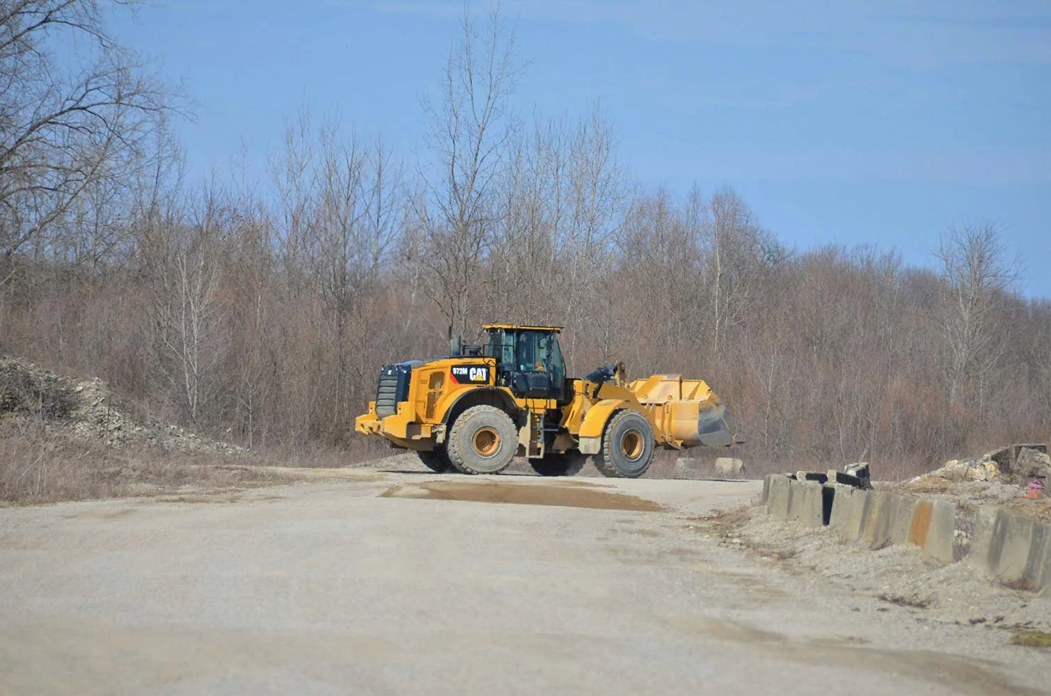 Wheel loader moving gravel across a clear worksite