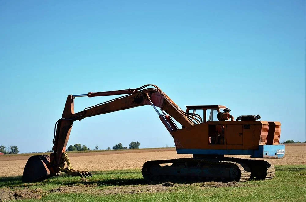 Excavator parked beside an open field