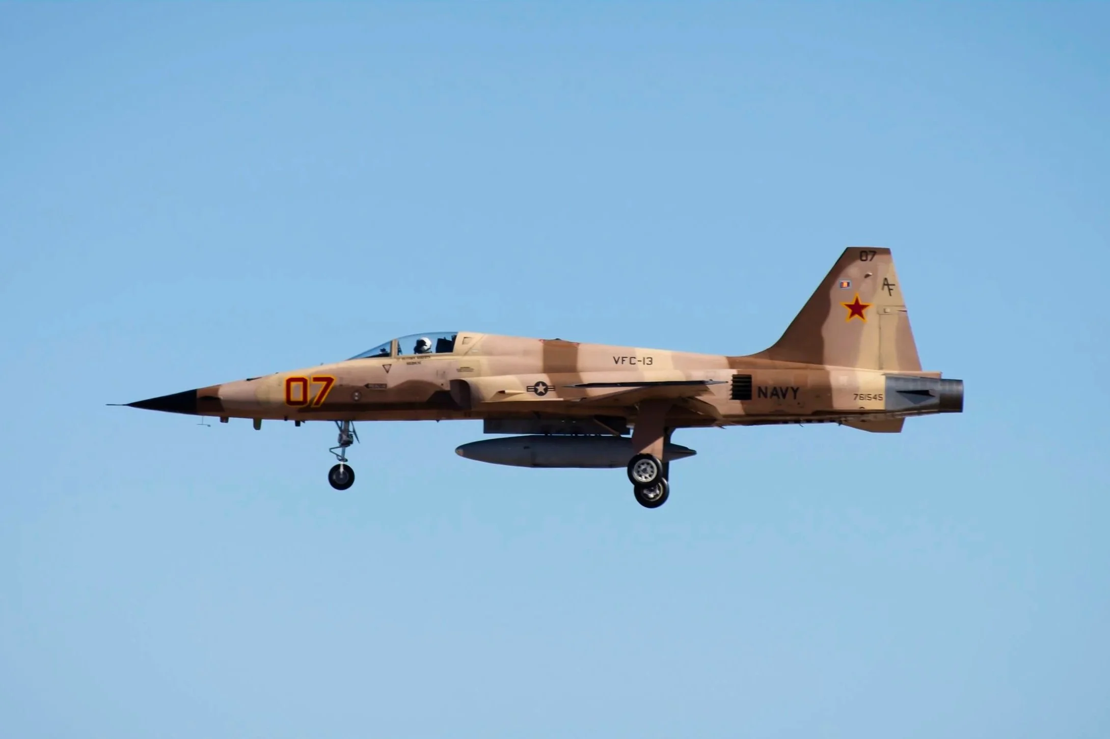 An F-5 Tiger flying in the sky with a blue background.