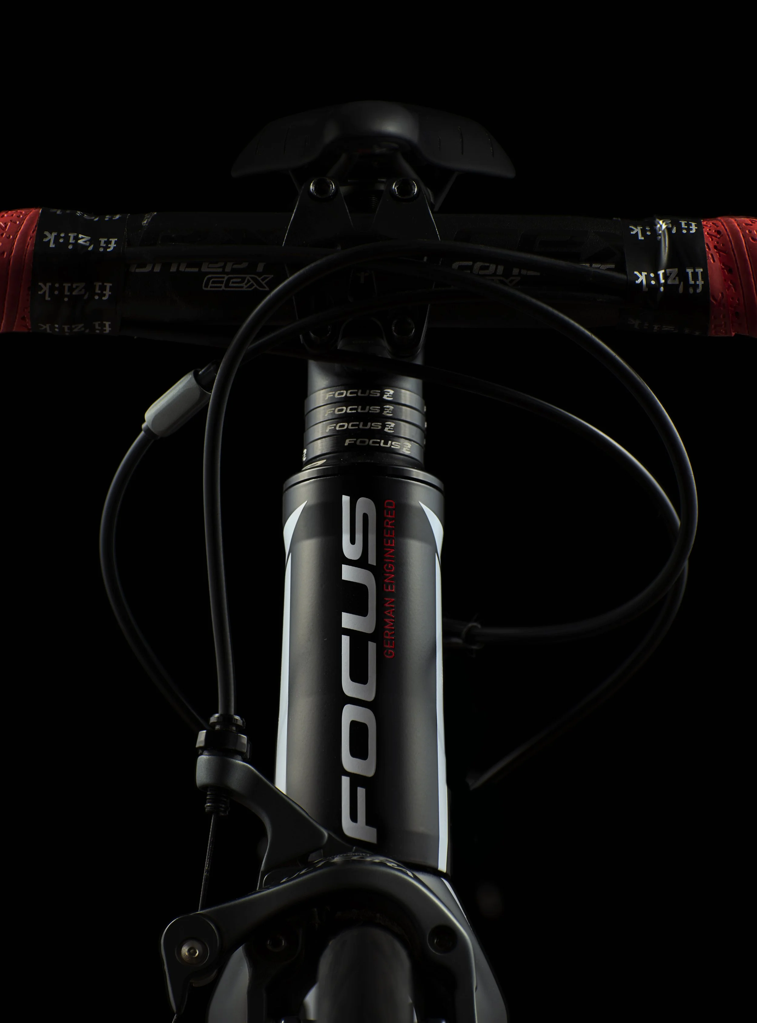 Close-up of a bike front fork with the brand 'FOCUS' visible, set against a black background.