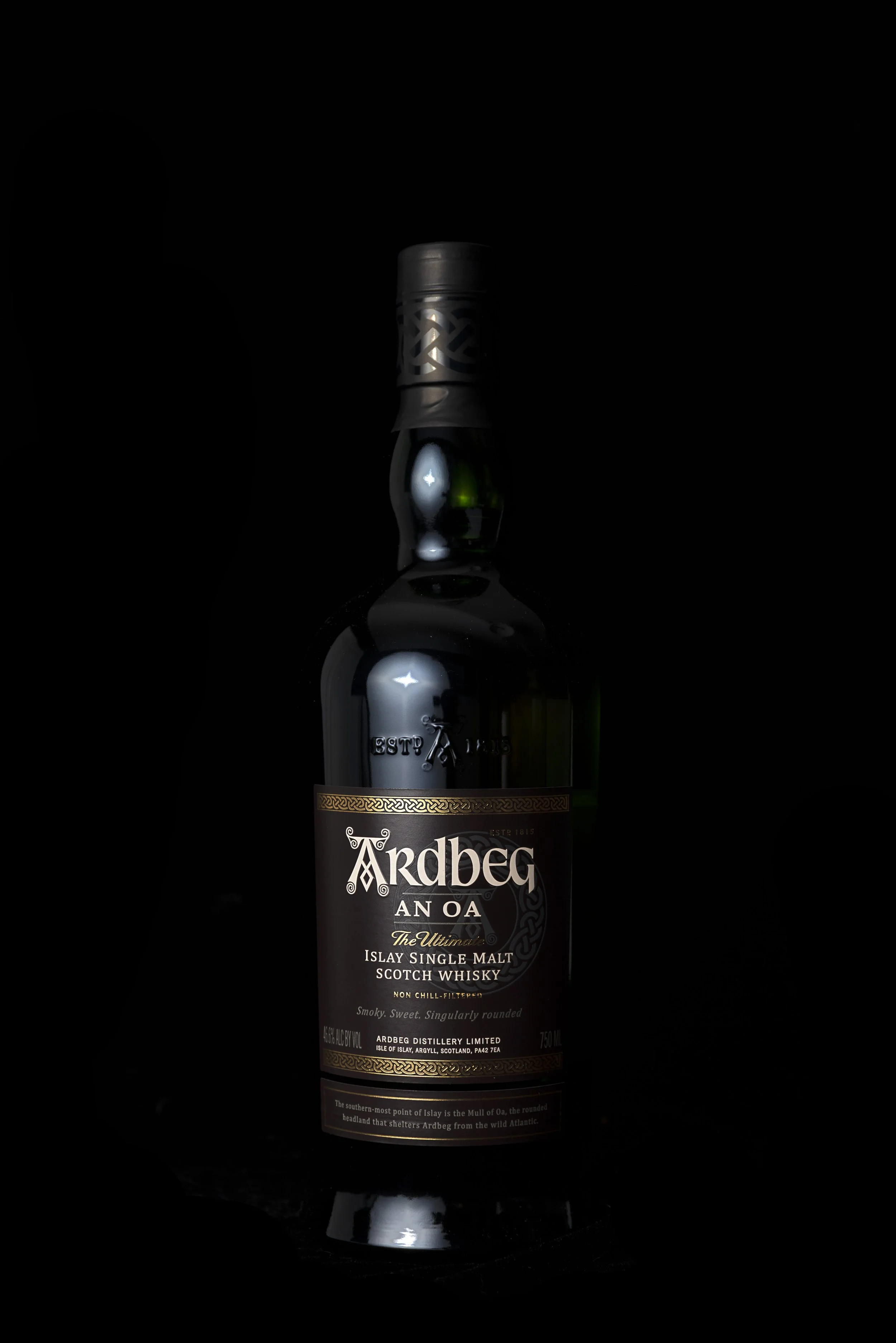 A bottle of Ardbeg An Oa Scotch whisky against a dark background, with a label detailing the brand, type, and alcohol content.