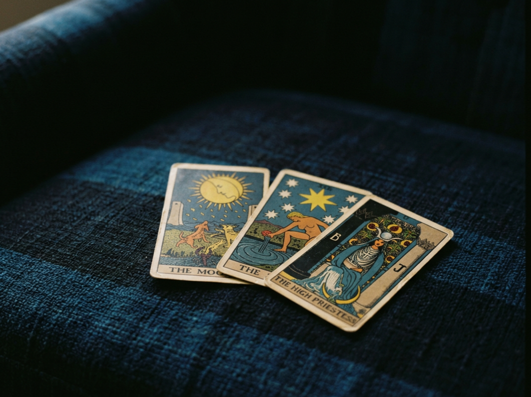 Four tarot cards spread out on a blue fabric surface, including The Moon, The Star, The High Priestess, and The Moon.