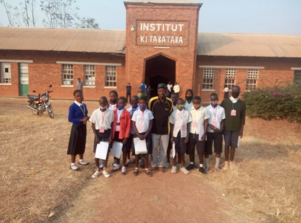 A group of students and two adults standing in front of the Kitabataba Institute building.