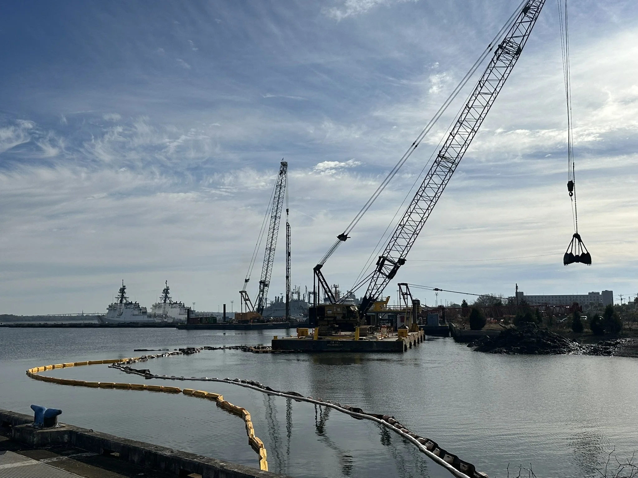 Crane pile driving from a barge on a marine construction project.