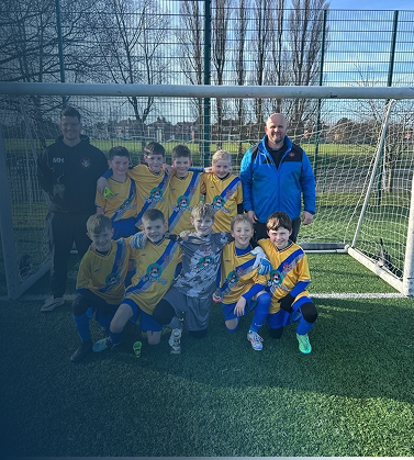 A youth soccer team of young boys in yellow and blue uniforms posing for a photo with two adult coaches on a soccer field.