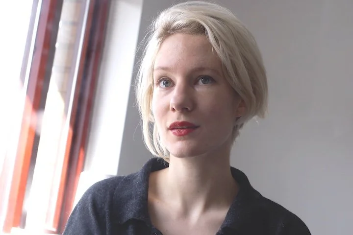 A woman called Freya with blonde hair, red lipstick and wearing a black shirt.