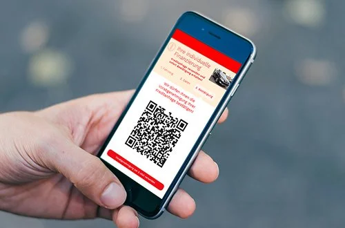 Hand hält ein Smartphone mit einem QR-Code auf dem Bildschirm.