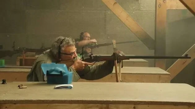 Deux personnes tirent avec des fusils à l'intérieur d'un stand de tir.