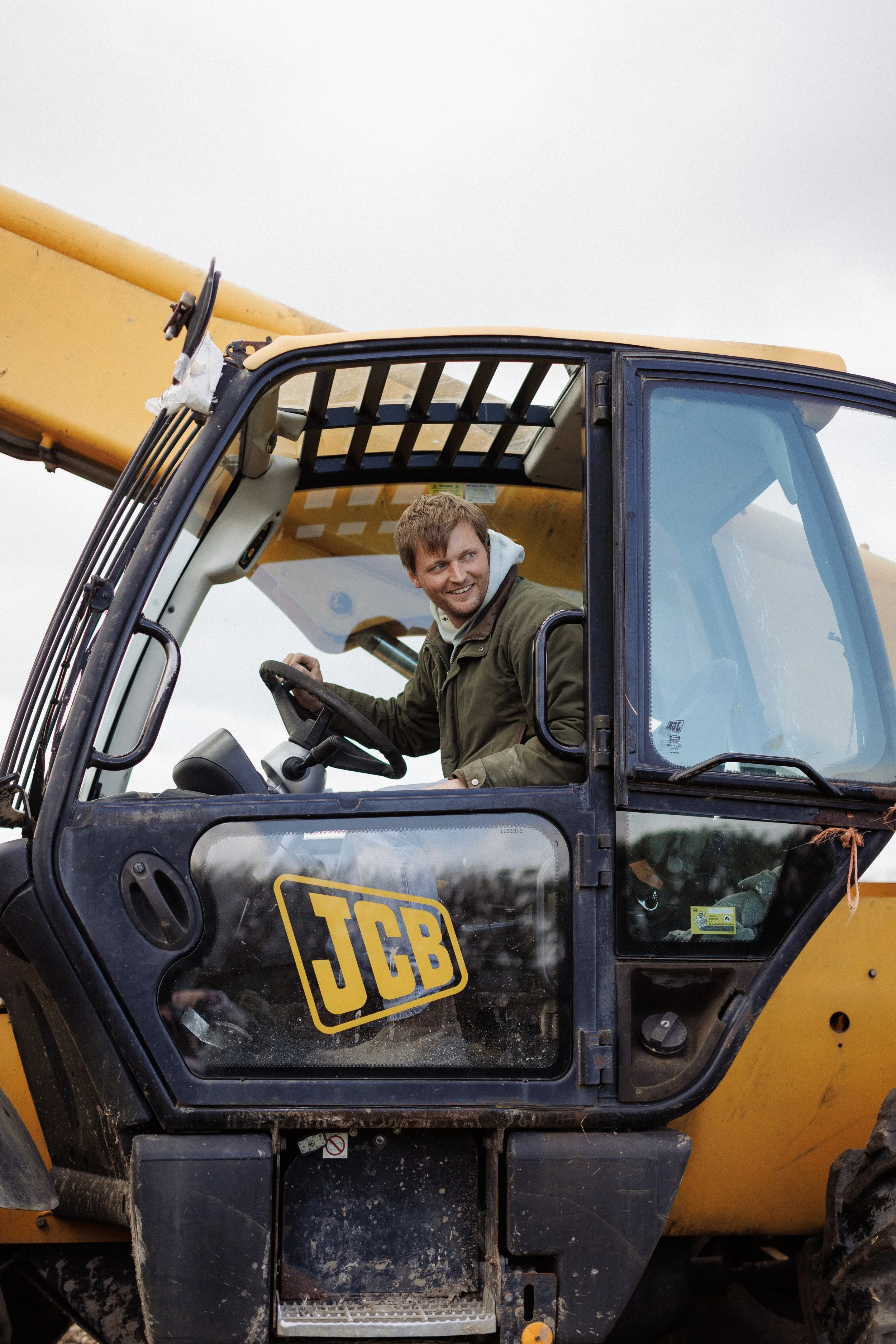 A man in a JCB smiling out of the cab.