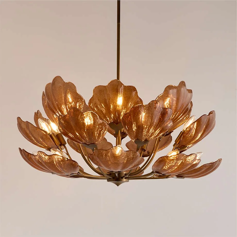 Sculptural amber glass chandelier from Crate & Barrel, featuring hand-formed floral petals that create a warm, luminous glow and dramatic organic silhouette.