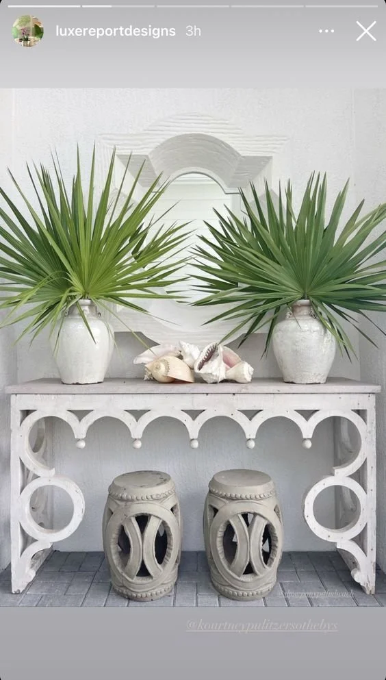 Tropical interior vignette with palm foliage, white pottery and collected coastal objects