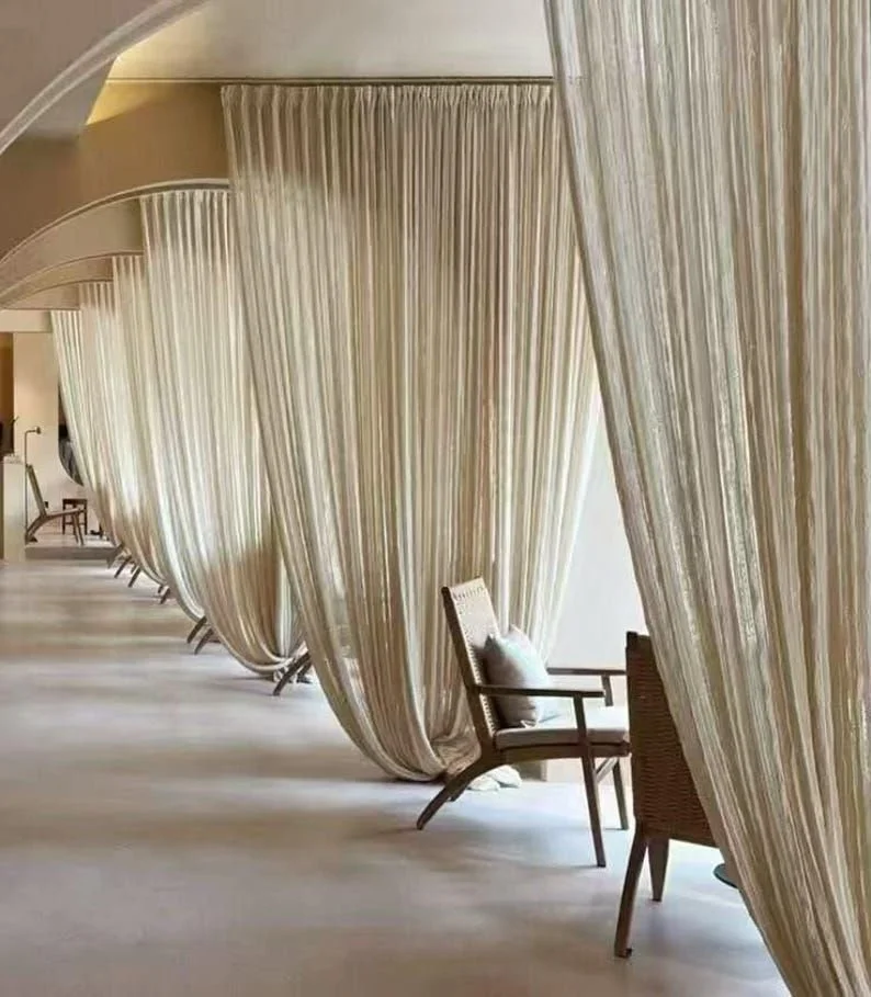 Row of private seating areas with beige curtains and wooden chairs in a luxurious hotel or spa lounge.