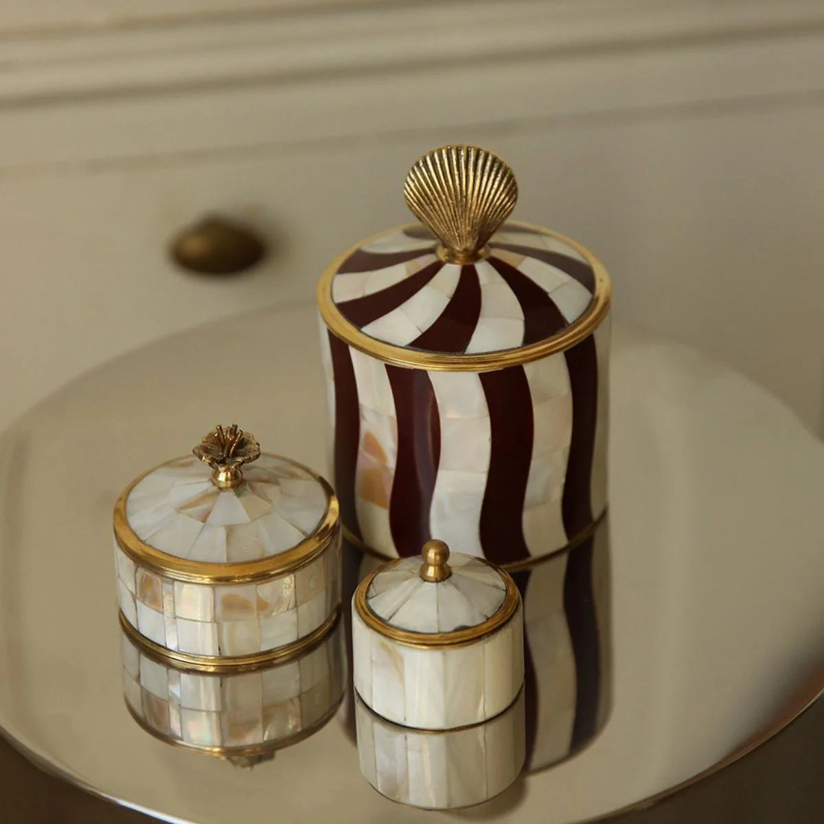 Abby Shell Circus Box by Doing Goods, through Maure, shown with pearlescent boxes. Burgundy stripes and gold-toned details lend playful coastal glamour.