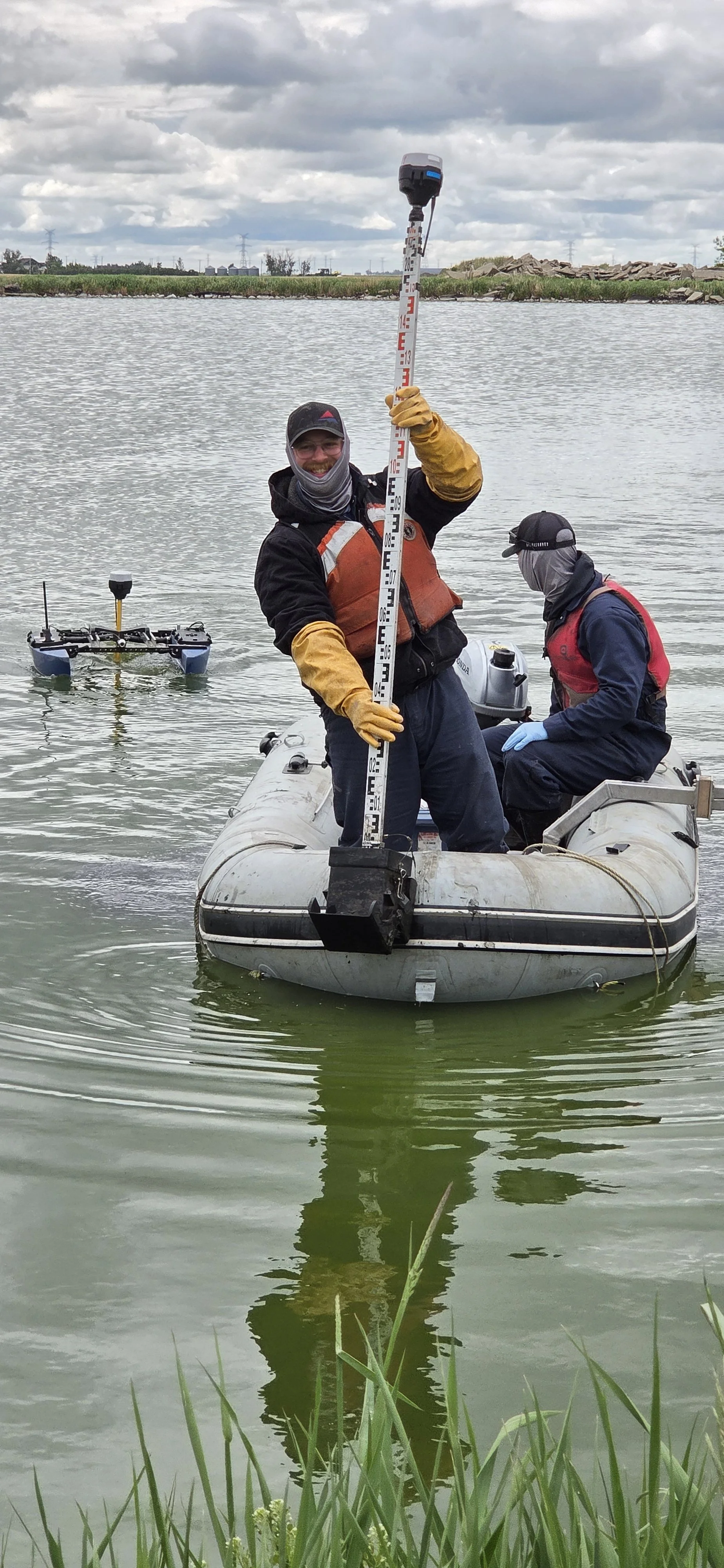 Field Technicians on an inflatable work boat conducting a sludge survey and collecting sludge samples using a sludge sampler built by Hydrasurvey