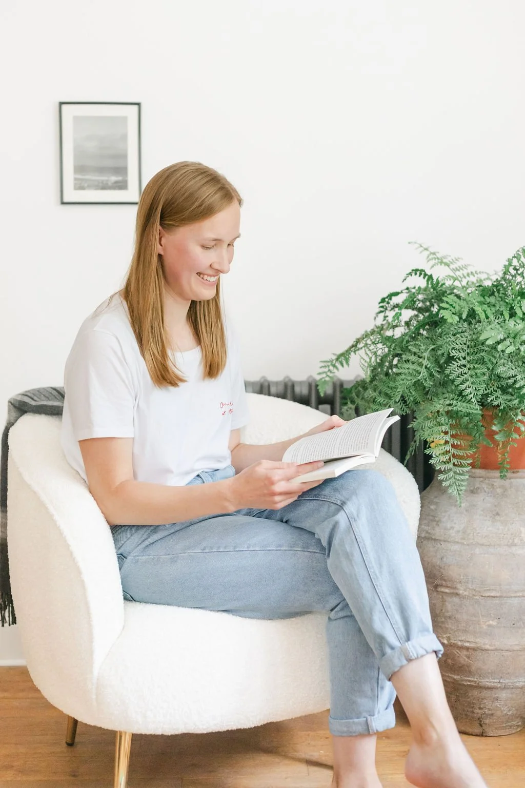 A therapist sitting on a cream-colored armchair, reading a book.