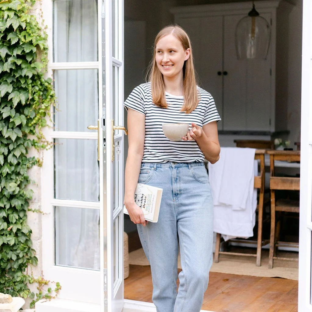 Sleep therapist standing in doorway holding book and mug