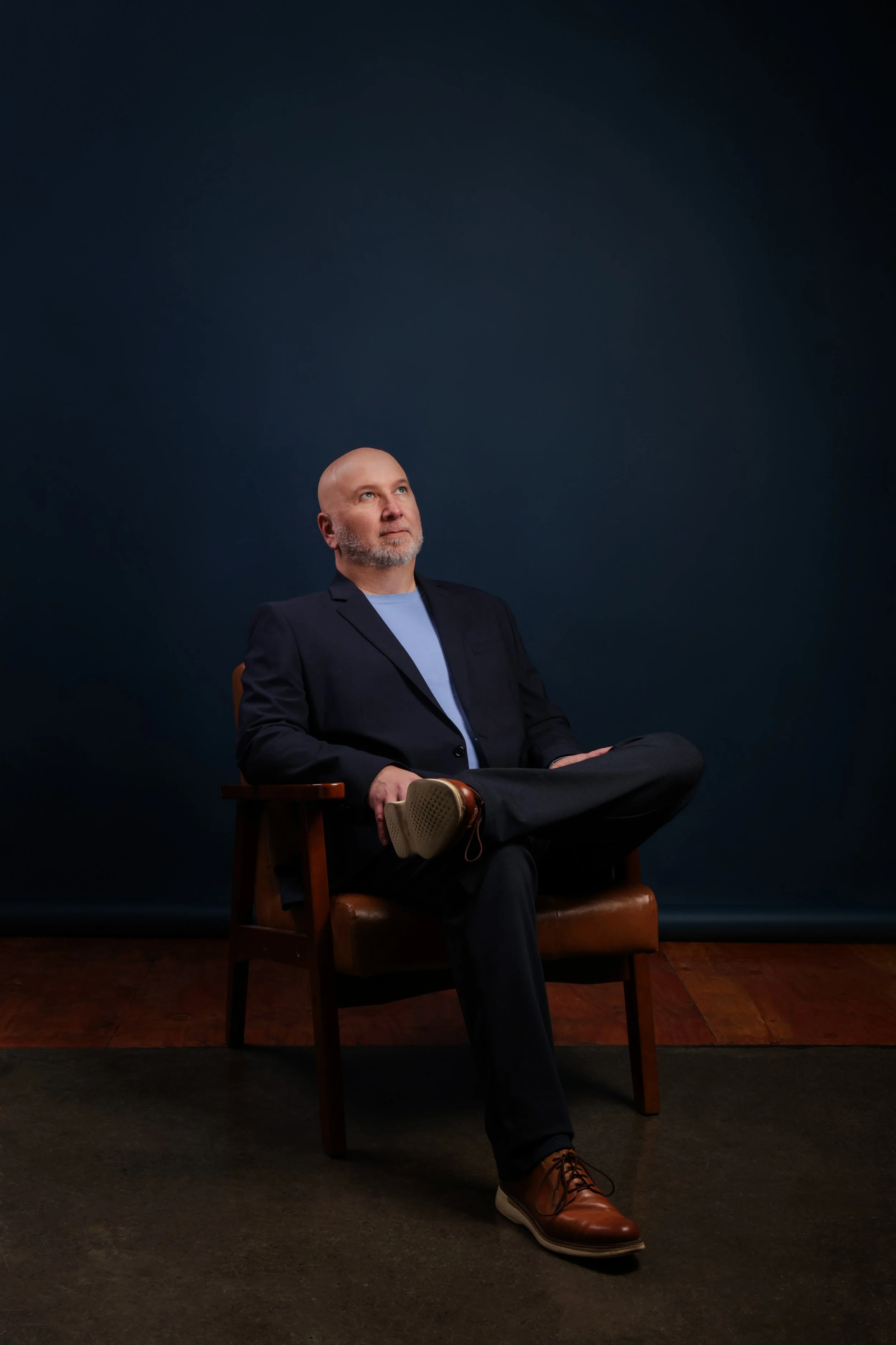 Alain Roy le stratège de ROY identité engagée assis sur un fauteuil, il réfléchit.