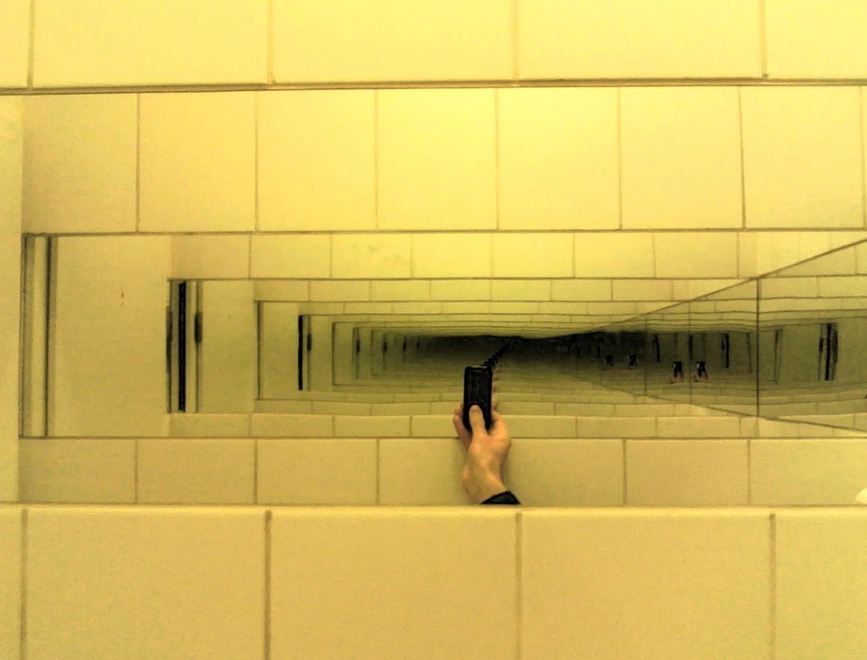 two mirrors facing each other with a hand taking a picture