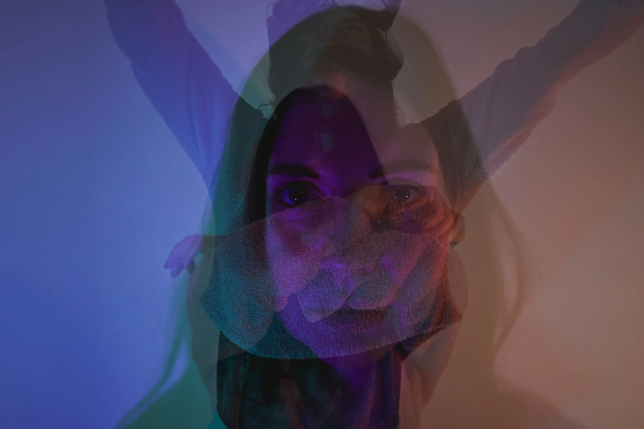 Double exposure image of a woman with long hair, with her arm raised, overlaid with colorful abstract shapes and light effects.