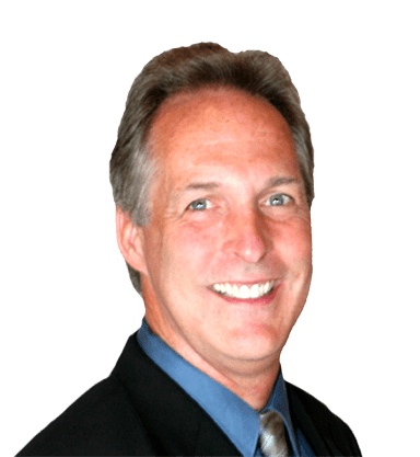 A smiling middle-aged man with short gray hair, wearing a dark suit, light blue shirt, and patterned tie.