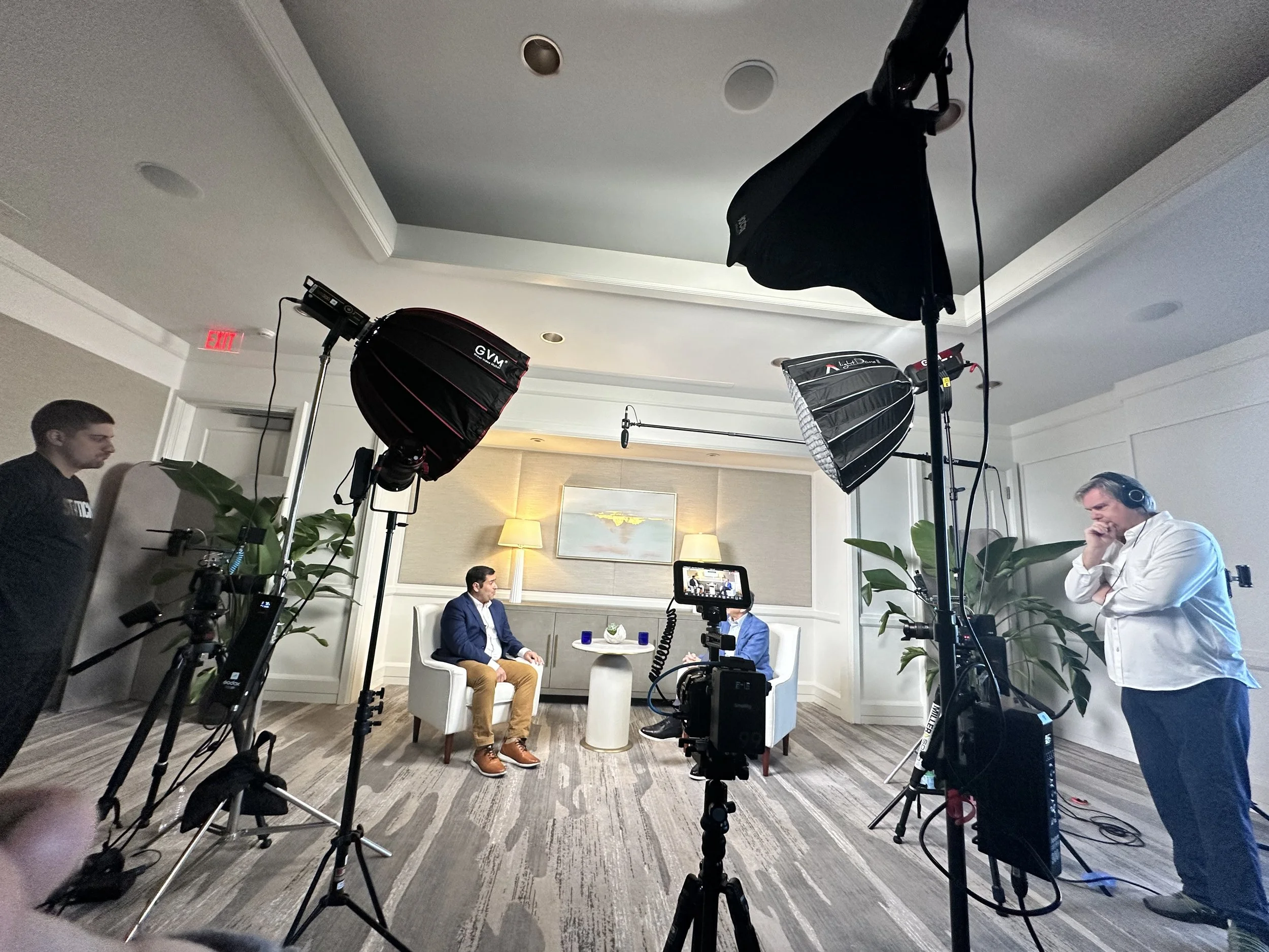 Director John Scoular filming at the Ritz Carlton Tiburon Naples with lighting equipment and crew members preparing or adjusting the setup.