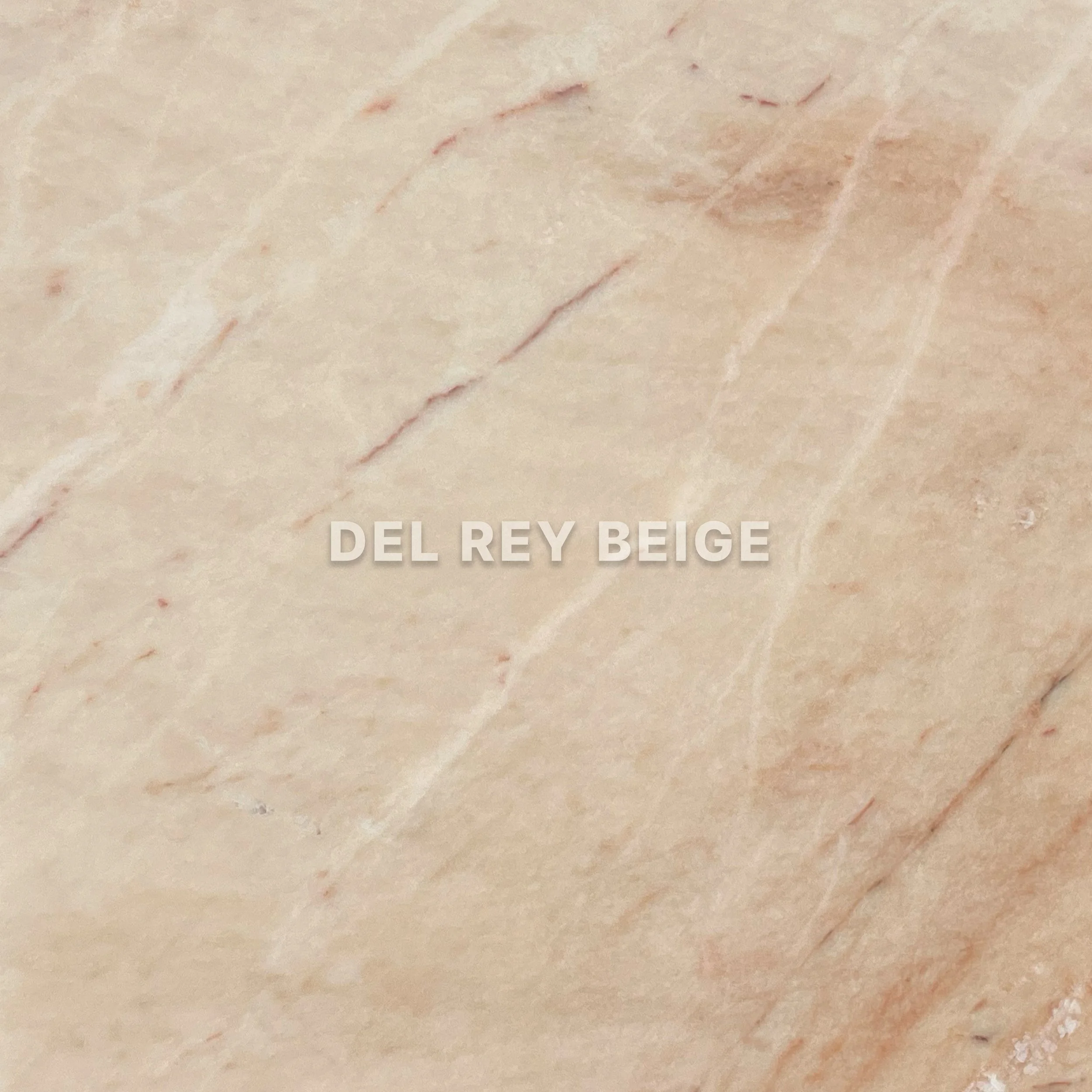 Close-up of beige marble with pinkish veins and the text 'DEL REY BEIGE' in the center.