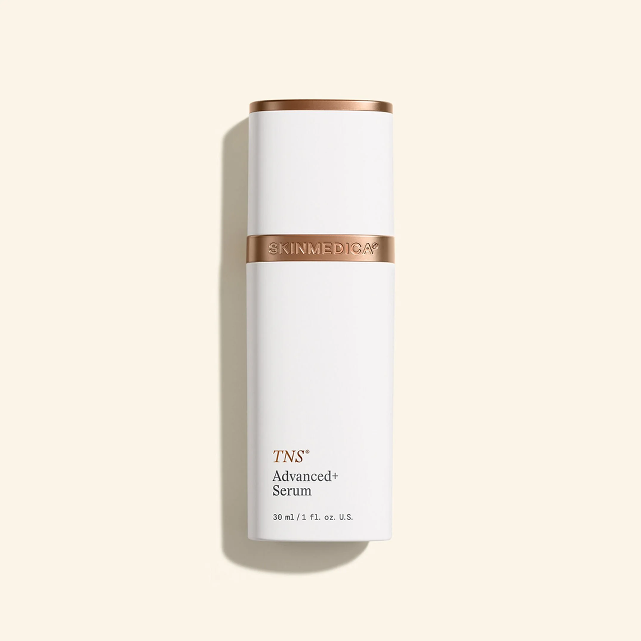 A white bottle with a gold-colored cap and a gold band around the middle labeled 'SKINMEDICA' and TNS Advanced+ Serum indicating a skincare product, with a light beige background.