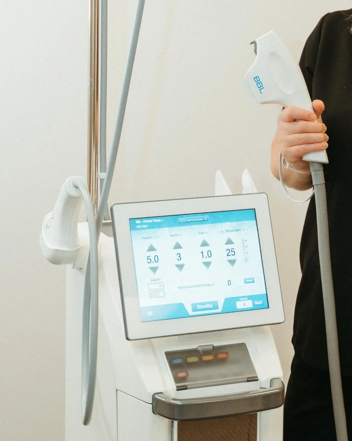 A Sciton MJoule laser device  and digital screen displaying settings, with a person holding a handheld laser device.