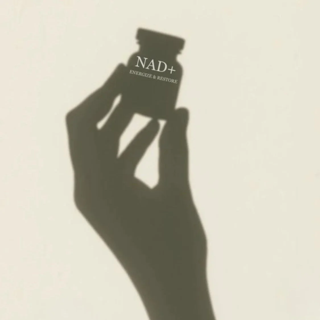 Shadow of a hand holding a small bottle labeled NAD+ with the text "Energize & Restore" on a plain background.