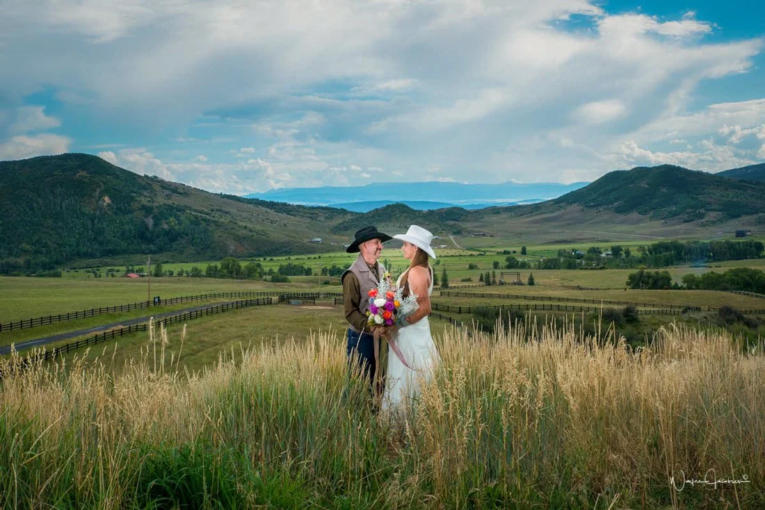 Couple in grass at main ceremony site overlooking mountain views at destination wedding venue in Colorado.