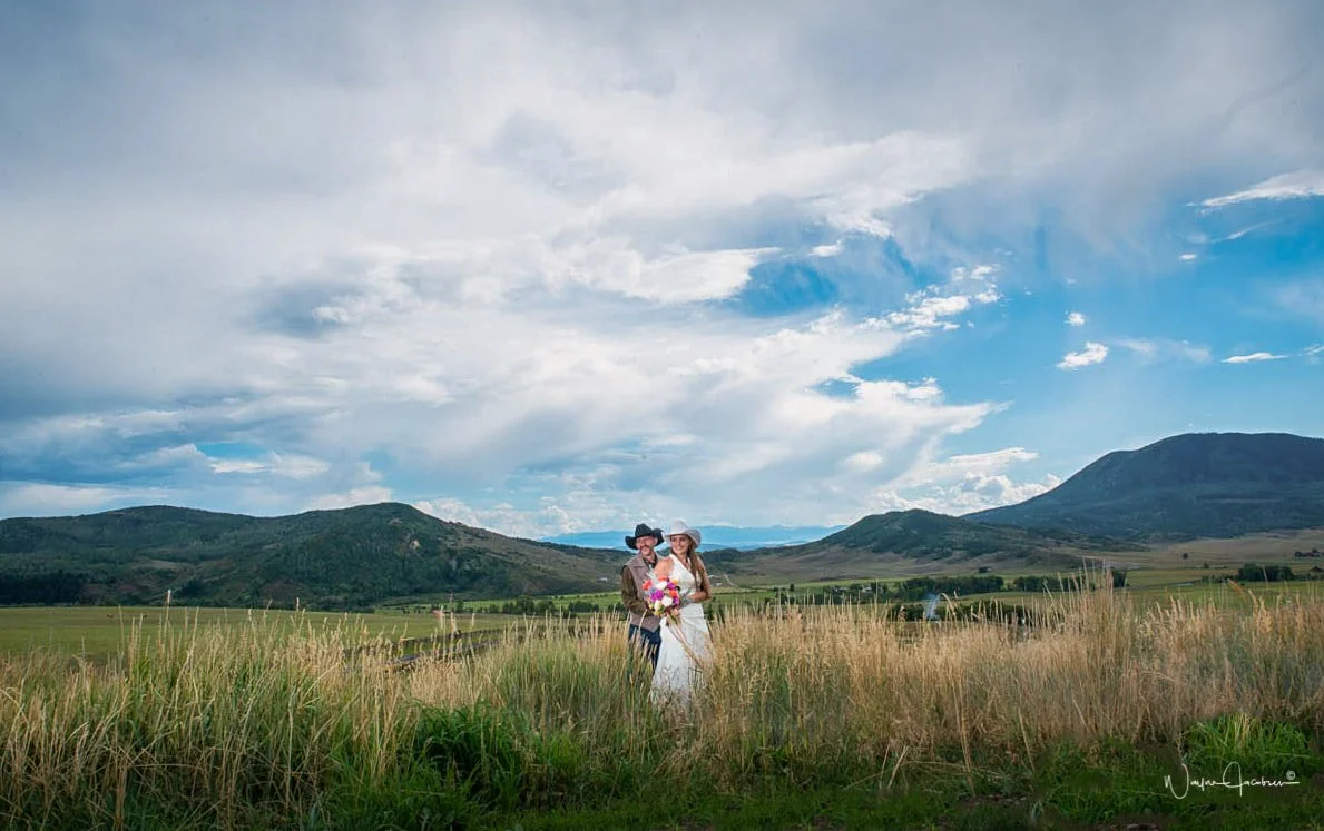 Couple in tall grass overlooking mountain views at luxury wedding venue in Steamboat Springs.