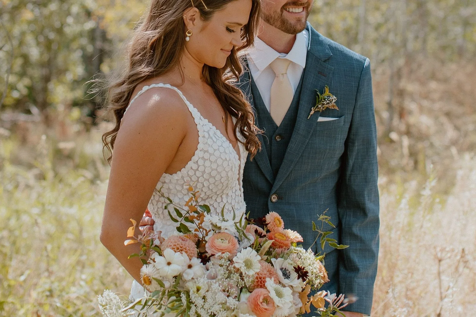 Bride looking down with bouquet while groom is holding her in aspen grove in Steamboat Springs