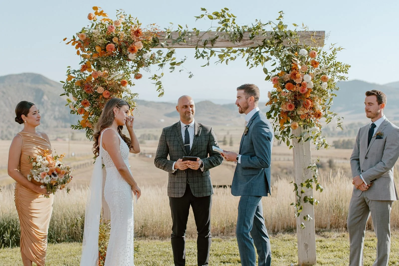 Couple exchanging vows with mountains in background at destination ranch wedding venue in Steamboat Springs