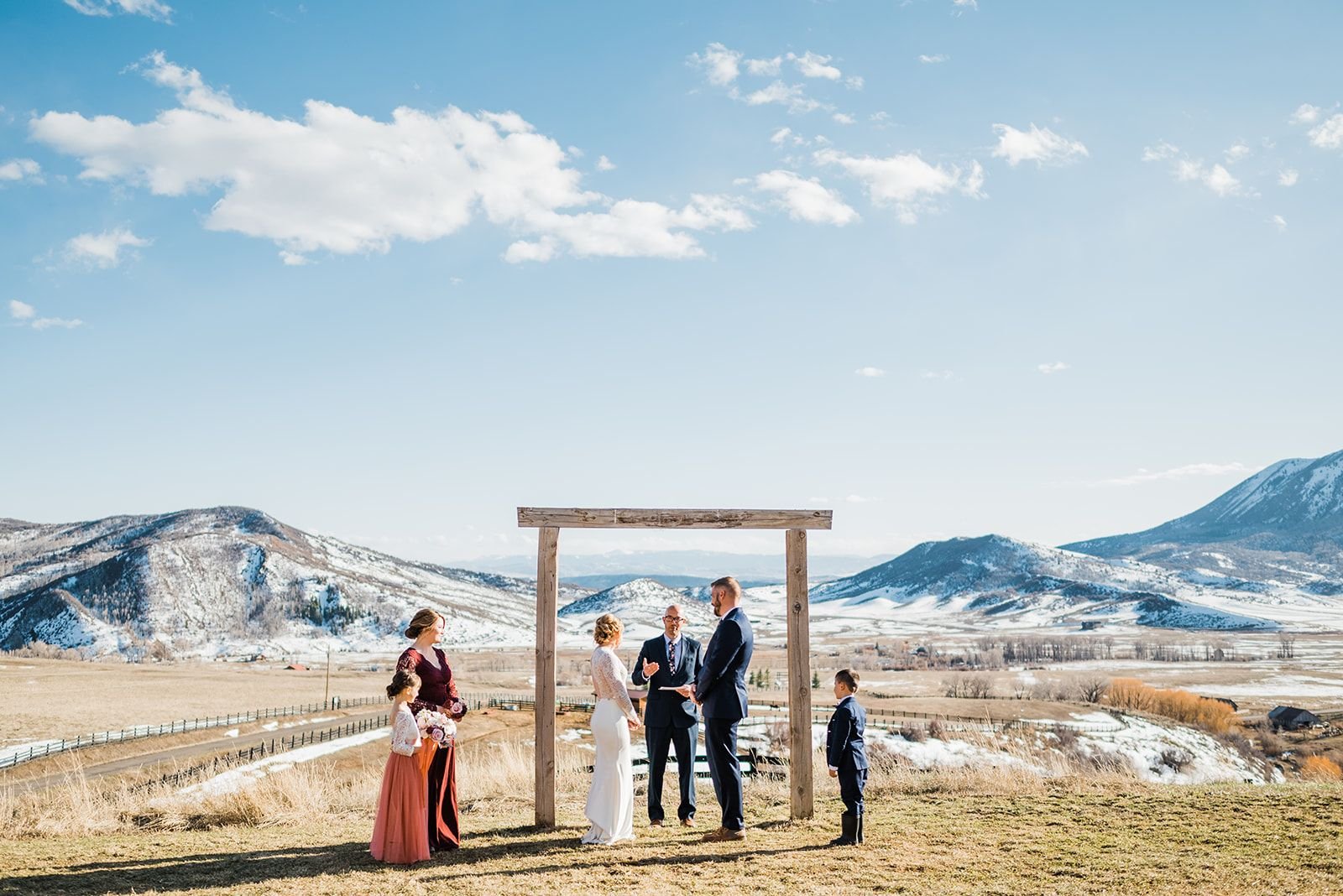 Bride and groom exchanging vows with snow and mountains in the background during their winter elopement at La Joya Dulce in Steamboat Springs, Colorado.