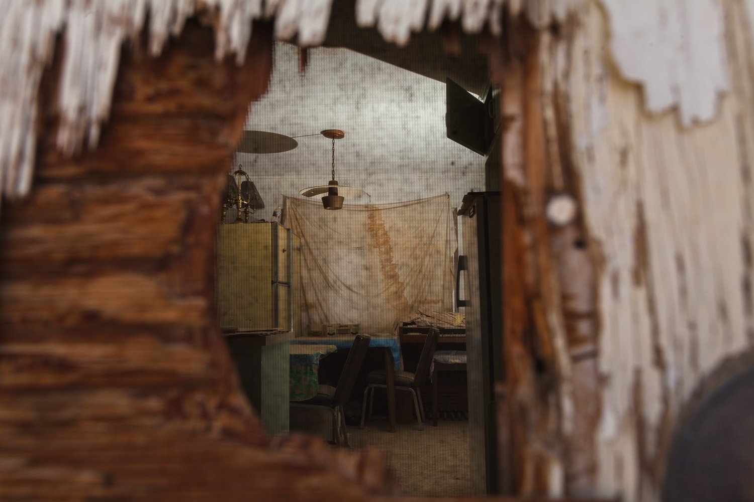 Peering through a punched hole in the front door of a home that was left intact as its occupants fled.