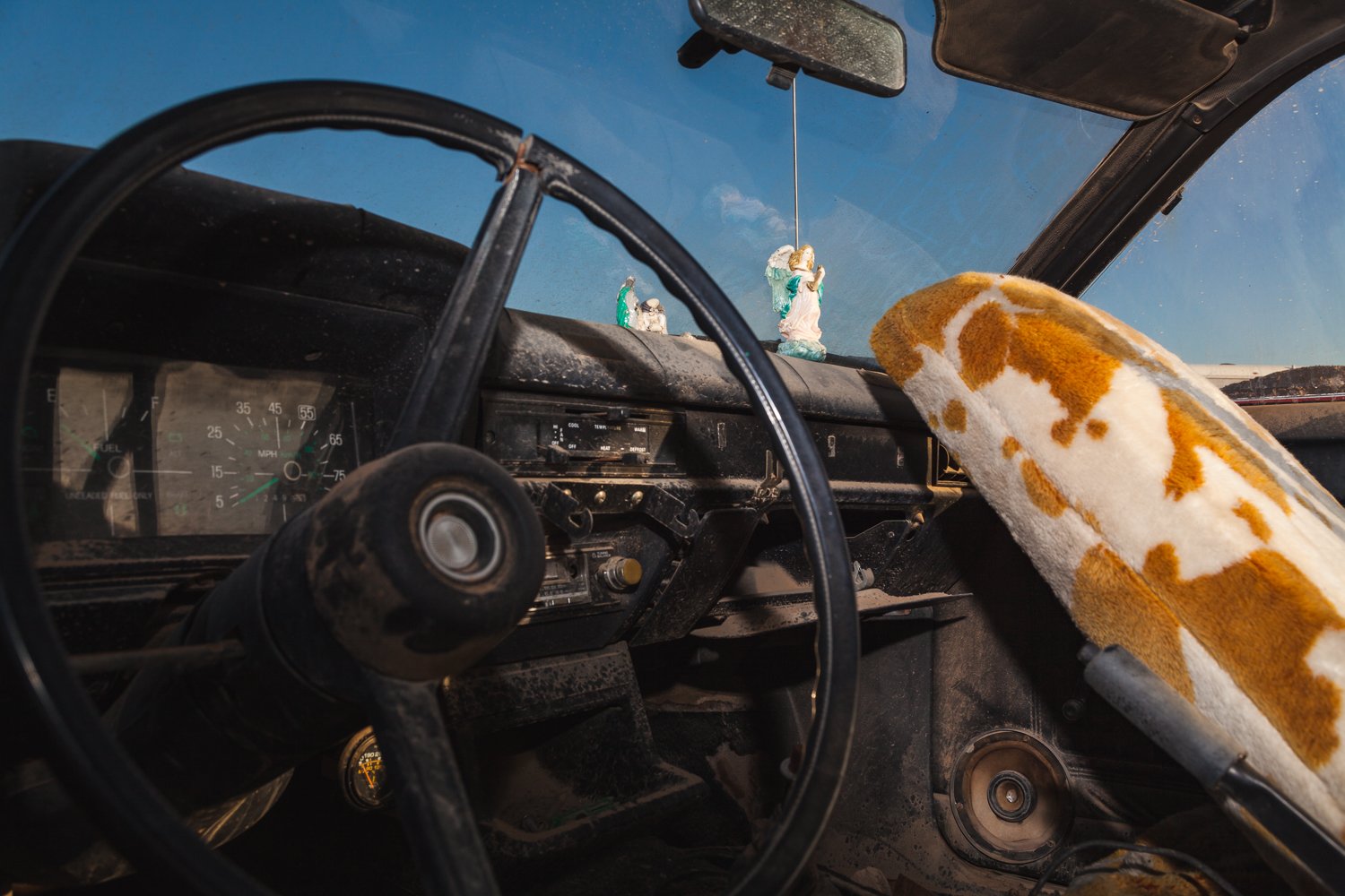 Angels adorn the dashboard of a long-abandoned vehicle baking in the desert California desert.