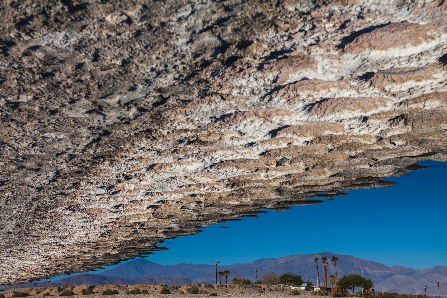 A house looms at the very edge of the polluted and stagnating water of the Salton Sea.