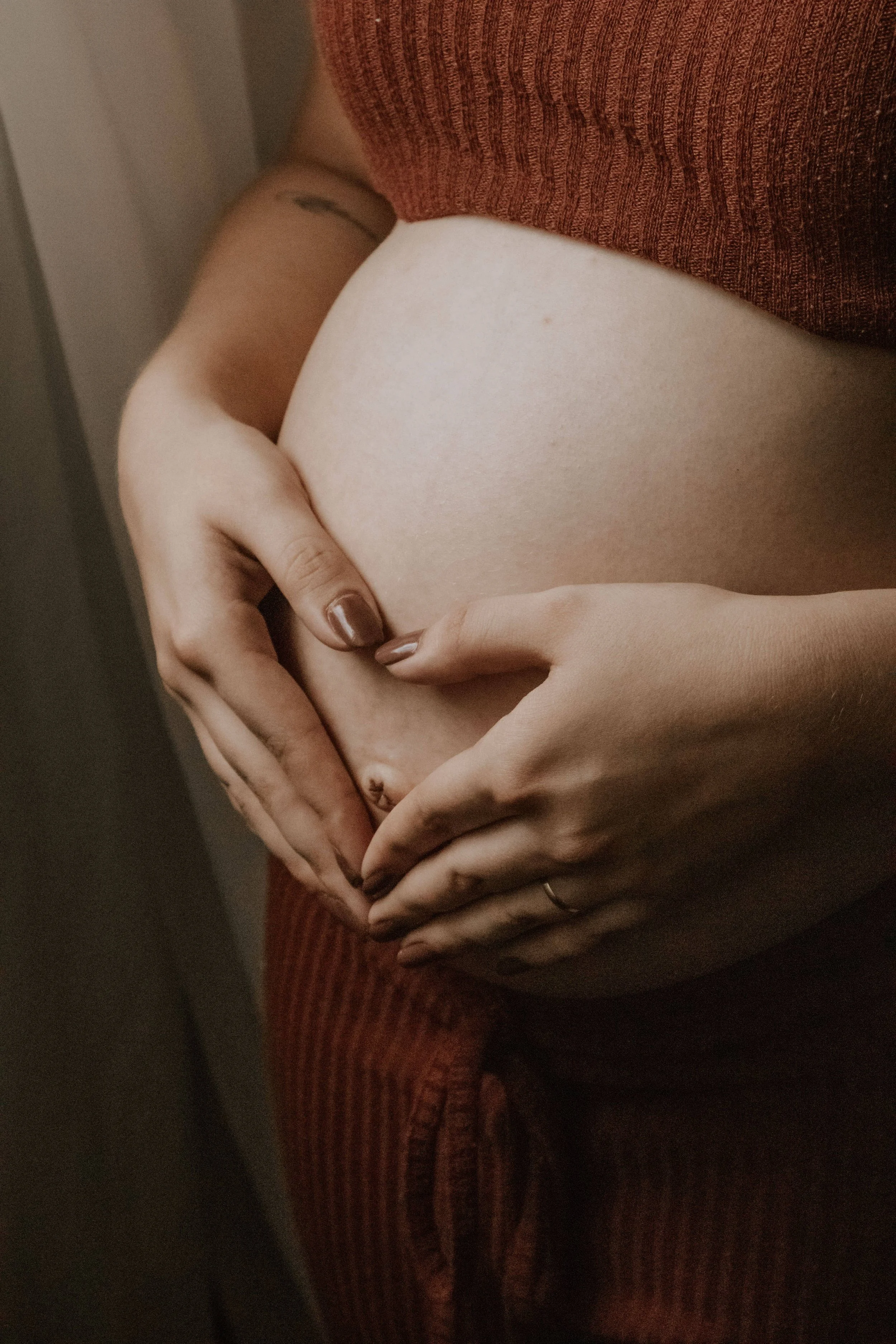 A pregnant woman, who has hired a birth and postpartum doula from The Breezy Doula, holds her stomach in Orange County.