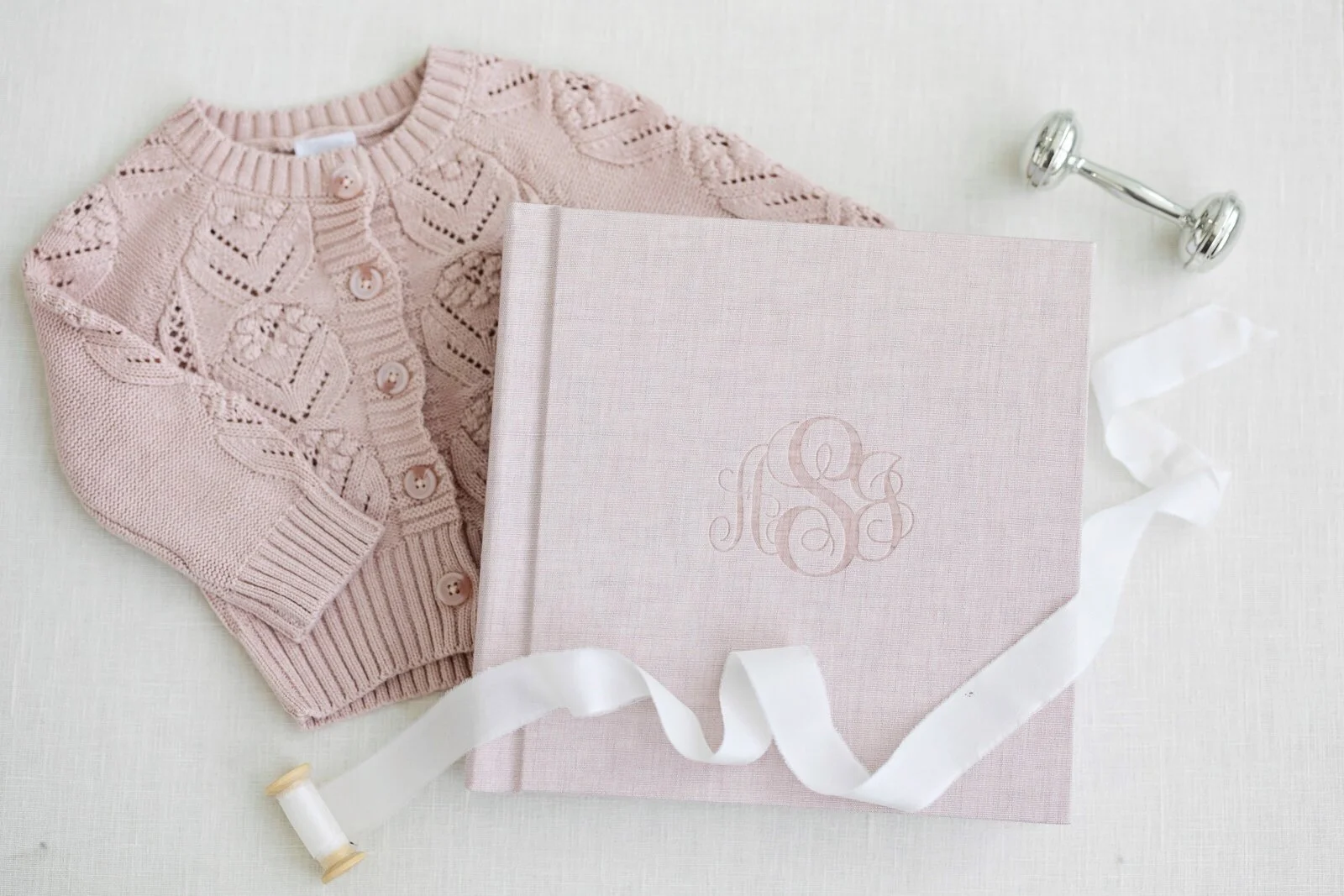 A pink knit baby sweater behind a scrapbook contain a placenta print provided by The Breezy Doula in Orange County, CA.