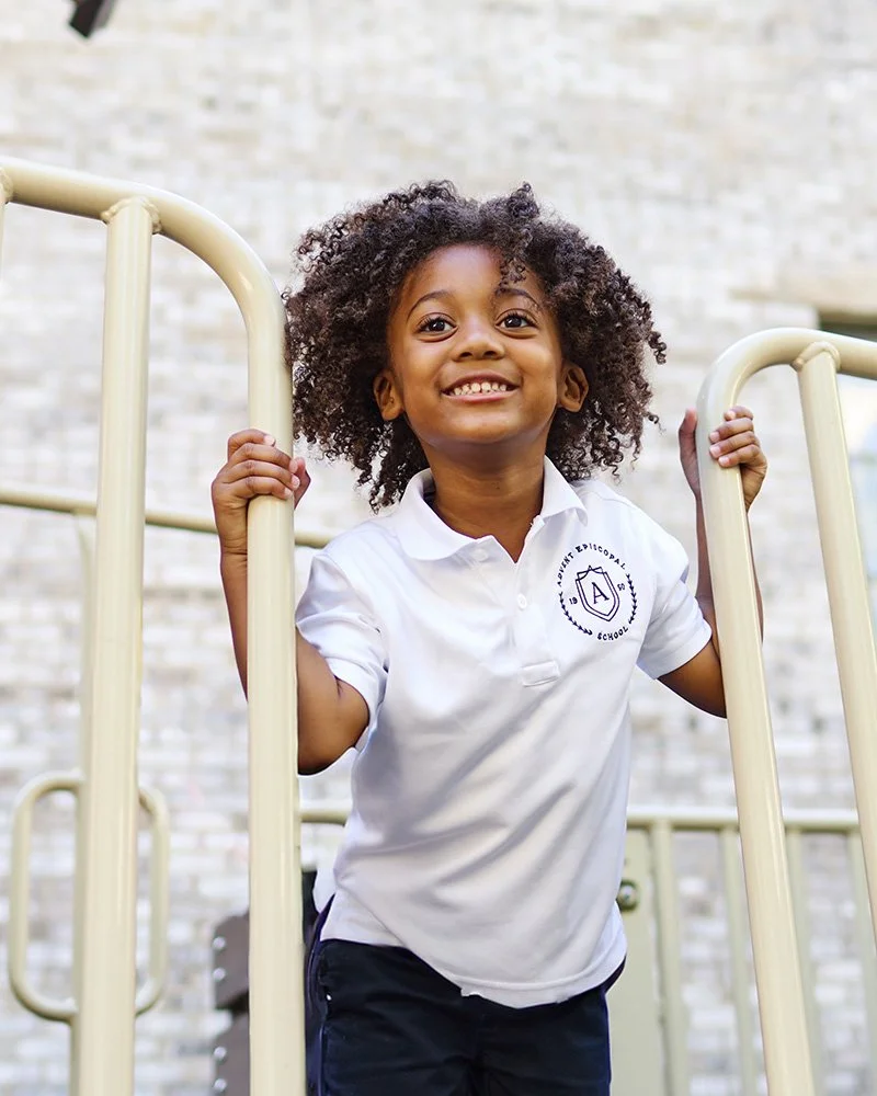 Smiling young girl with curly hair on playground equipment at school