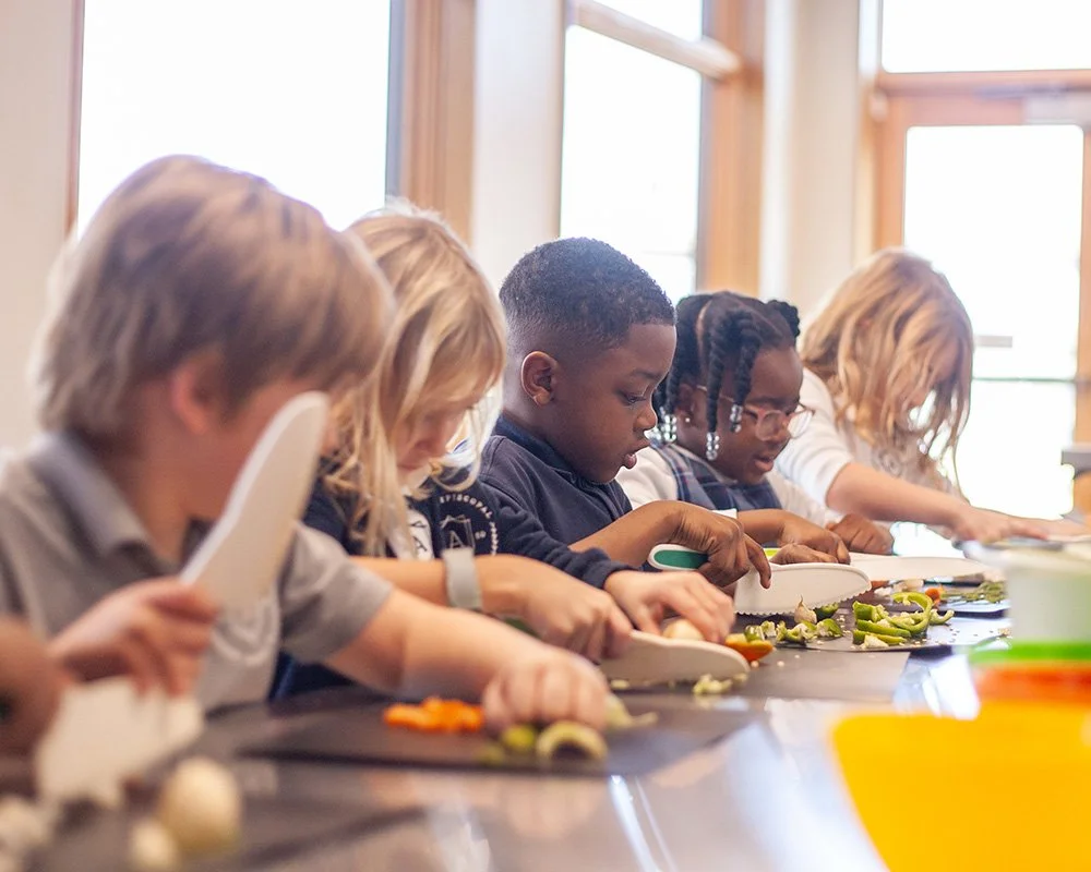 Children chopping vegetables at a table in a cooking class at Jones Valley Teaching Farm.