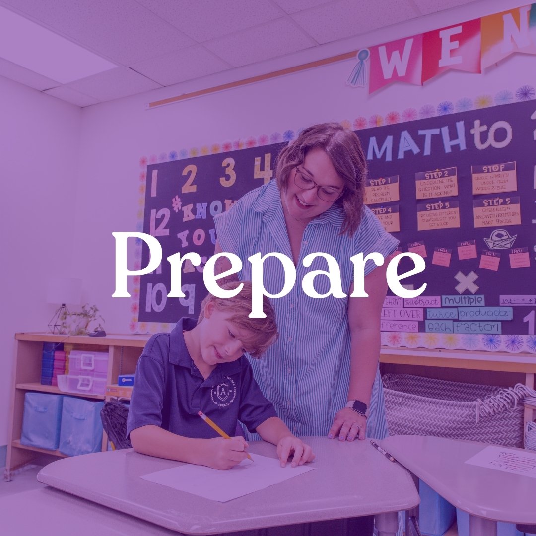 A woman and a boy in a classroom with a blackboard, colorful decorations, and educational posters. The boy is writing on paper and the woman is supervising.