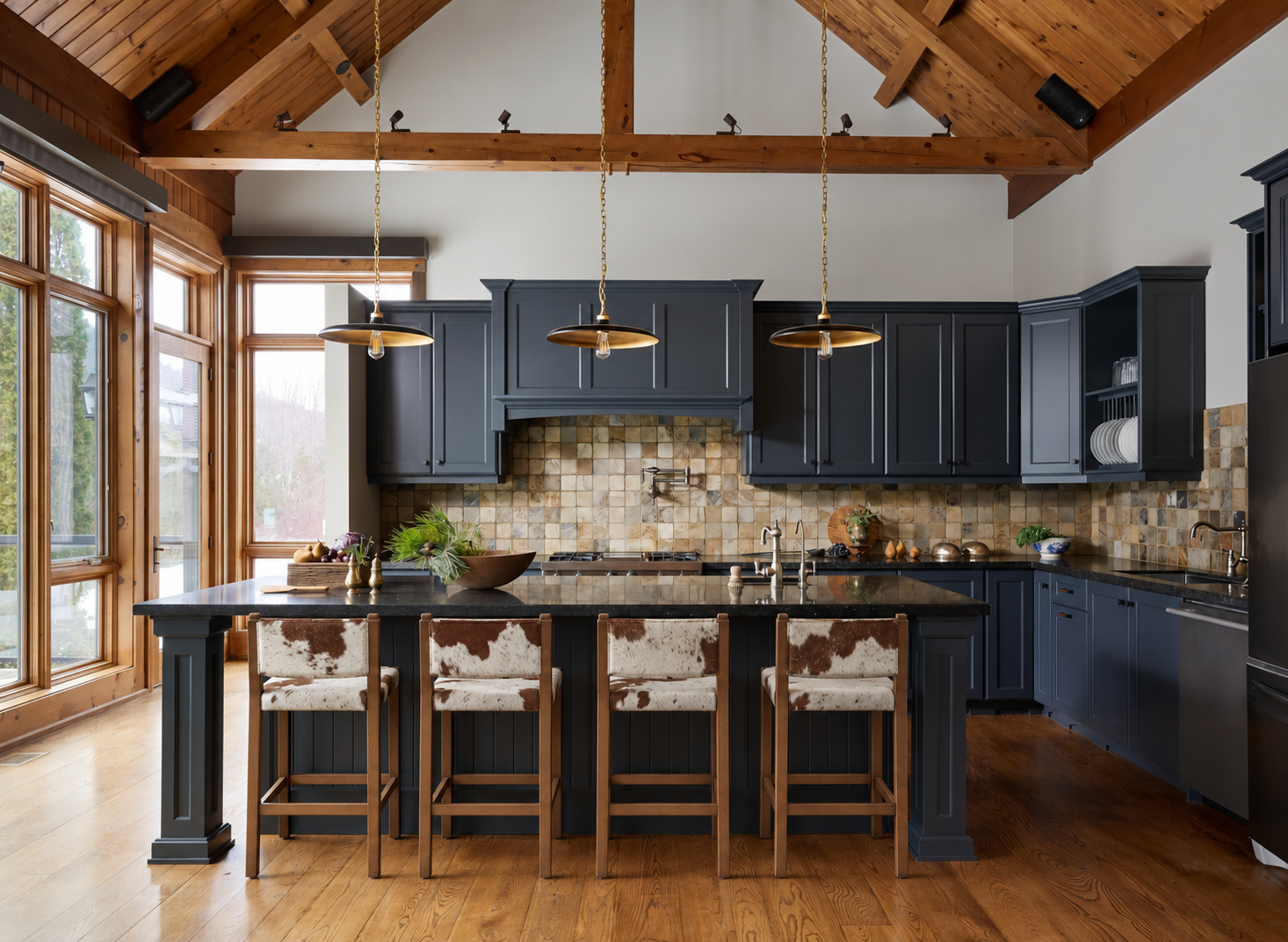 Chalet kitchen with dark cabinets, island with cow hide bar stools, pendant lights, and large windows.