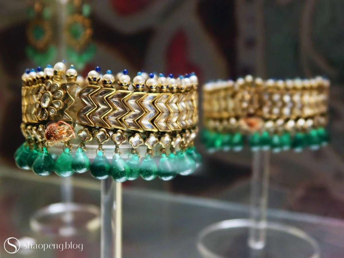 A pair of anklets set with diamonds, emeralds, and pearls.
