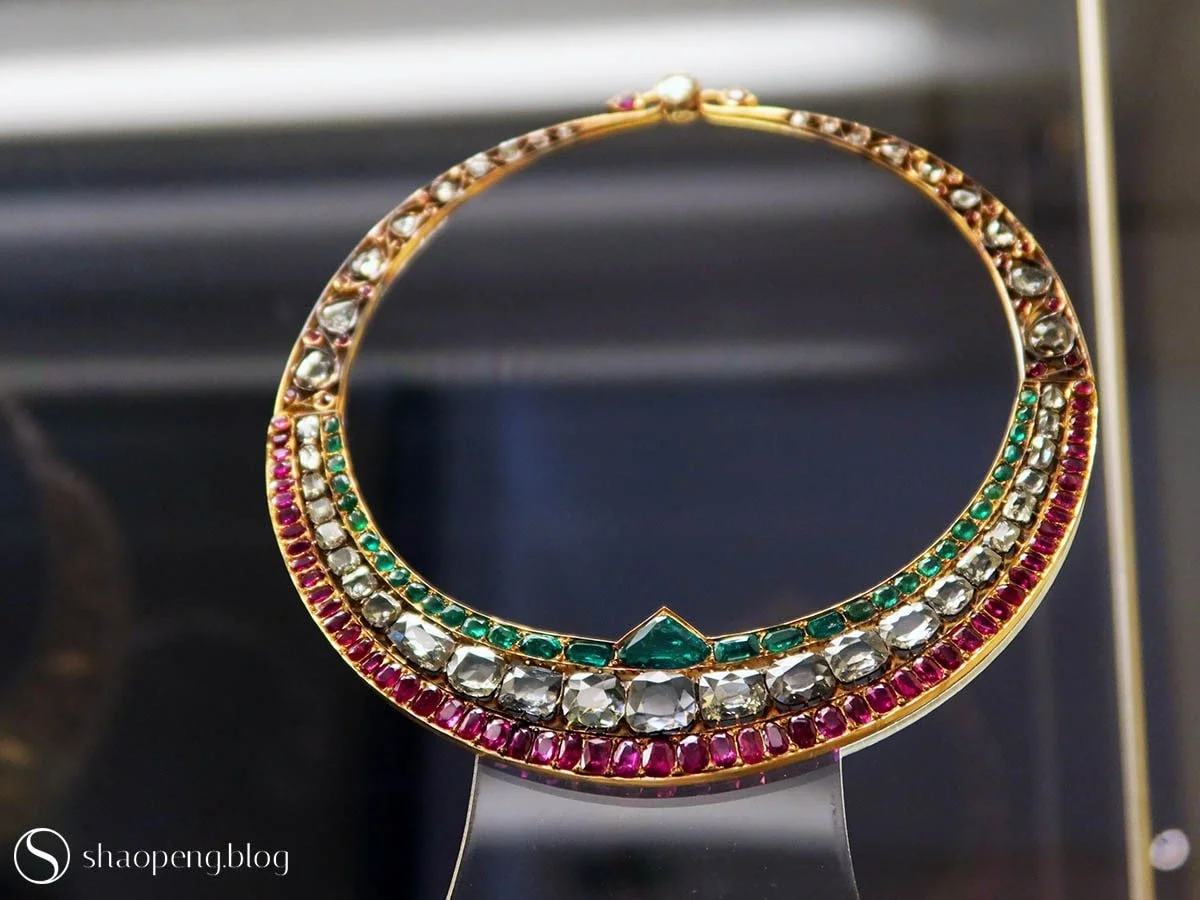 This necklace, set with emeralds, diamonds, and rubies, speaks a timeless style.