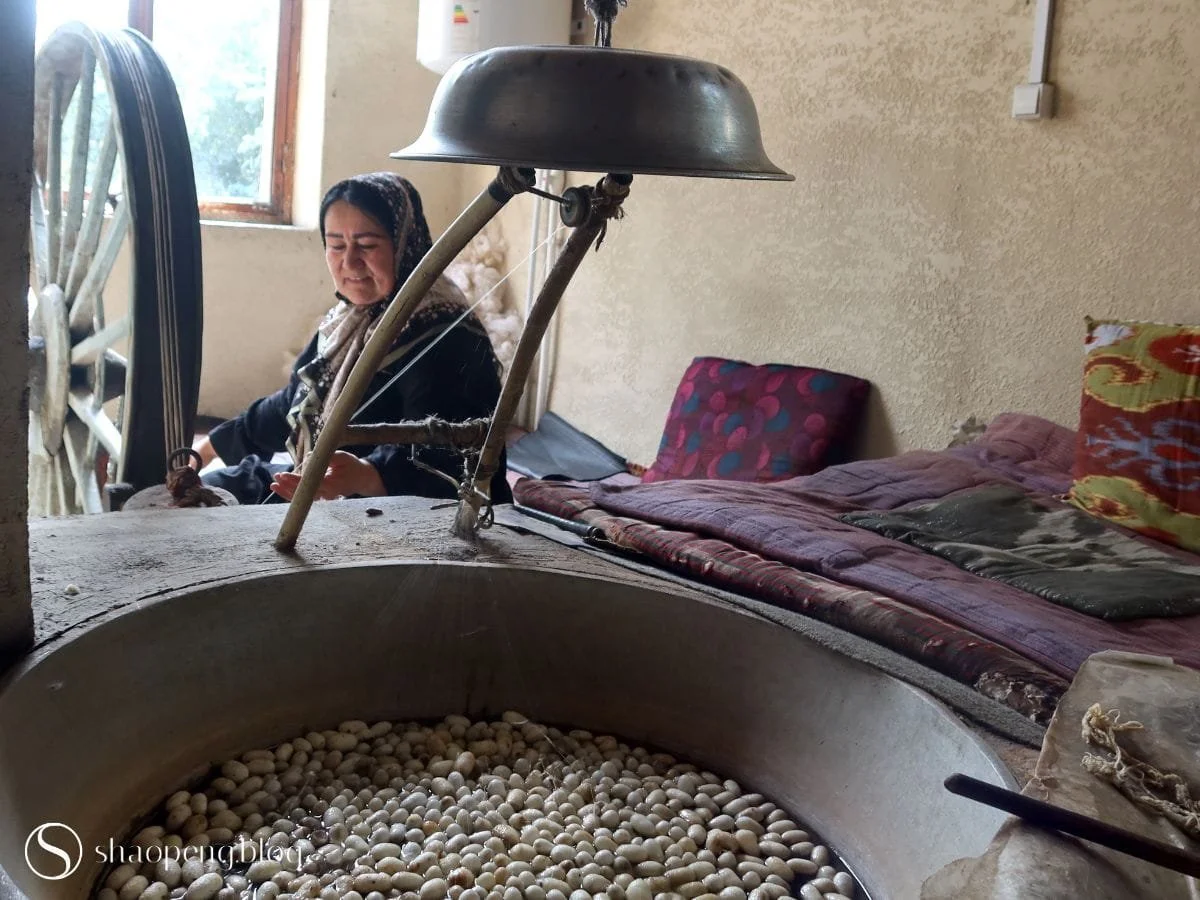 Artisan drawing and spinning silk thread from boiled cocoons at Yodgorlik Silk Factory in Margilan